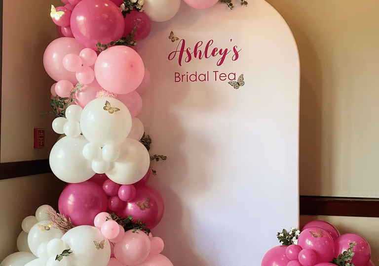 A beautiful organic balloon garland in blush pink and ivory shades used as a bridal shower table backdrop.