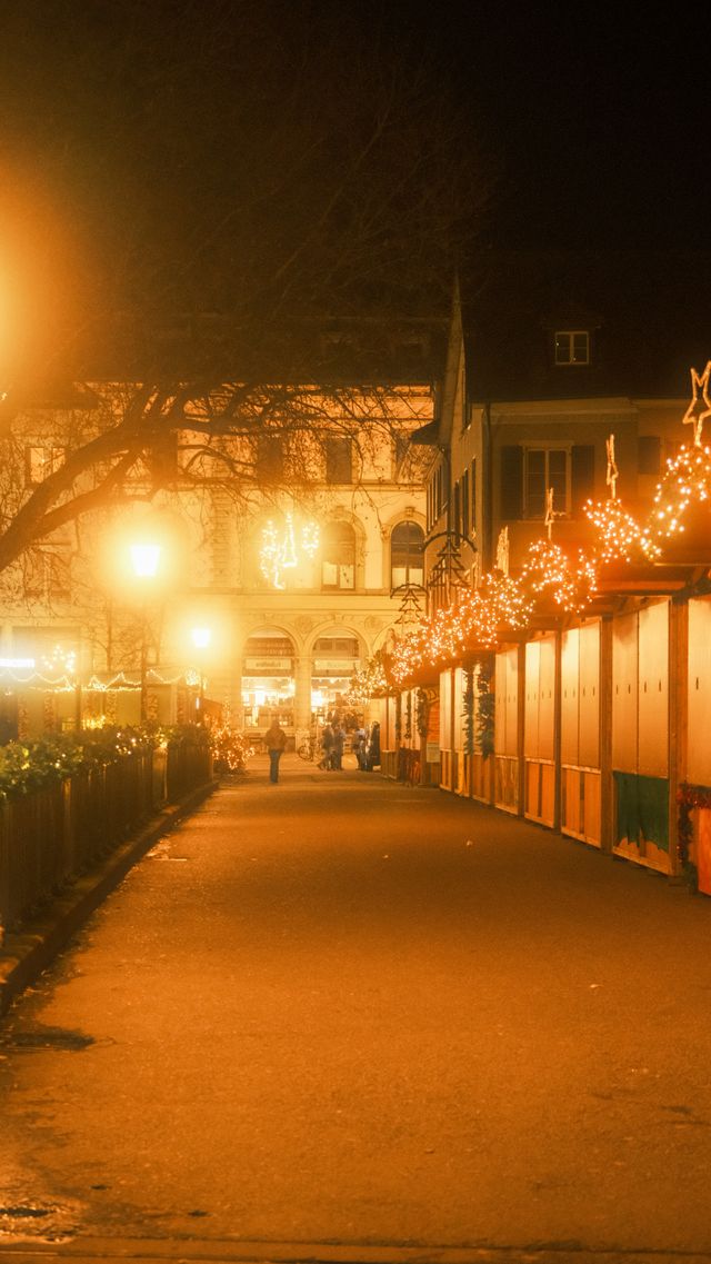 High-angle photograph of festive warm lighting and wooden chalets at the Bristol Christmas Market at night.