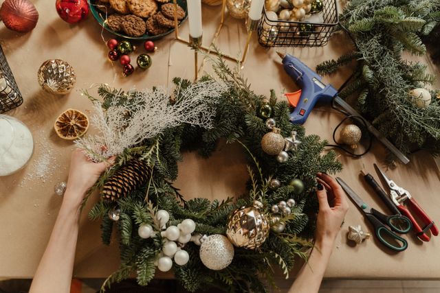 Wiring evergreen foliage onto a wreath frame during a DIY Christmas wreath build